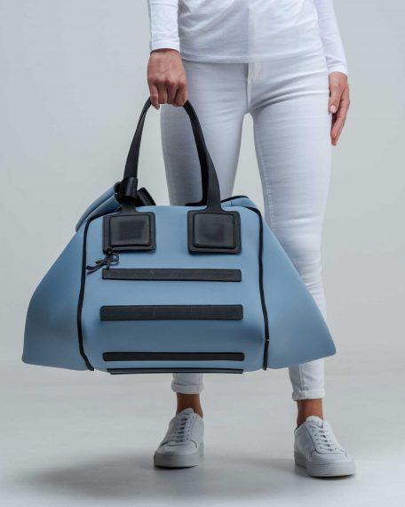 Una borsa lavabile effetto neoprene della collezione Travel di APbag prodotta da Artpelle e disegnata dal designer Stefano Galandrini. Nella foto, la modella indossa a mano una Travel Bag grande di colore carta da zucchero