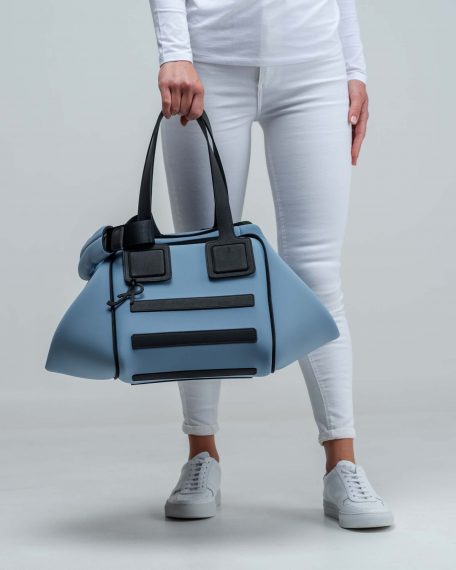 Una borsa lavabile effetto neoprene della collezione Travel di APbag prodotta da Artpelle e disegnata dal designer Stefano Galandrini. Nella foto, la modella indossa a mano una Travel Bag piccola di carta da zucchero